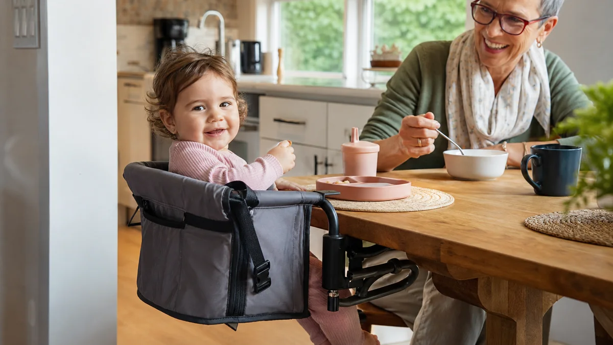 portable travel high chair shown in the real-life setting: Meals happen at a grandparent’s table, a rental kitchen, and an occasional picnic table.