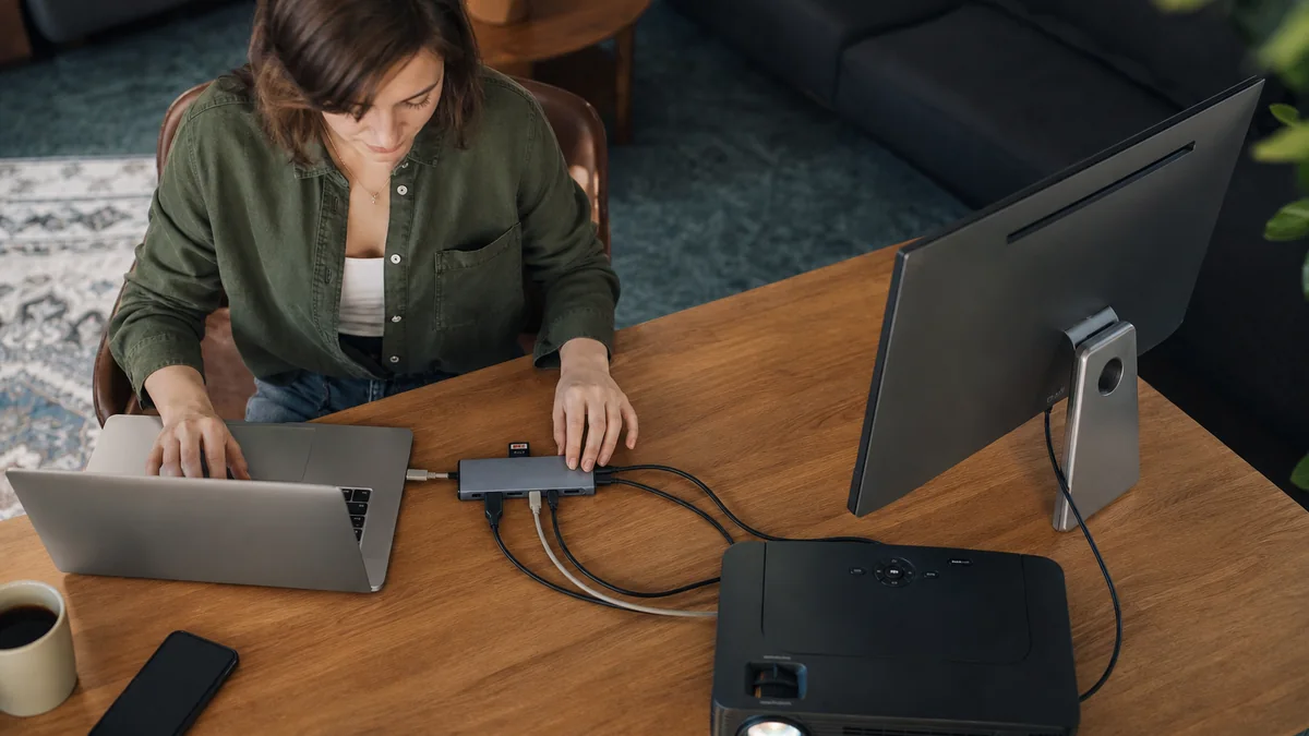 usb c hub multiport shown in the real-life setting: One laptop has to connect to a monitor at home, a projector at work, and an SD card on the road.